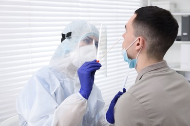 Photo of Laboratory testing. Doctor in uniform taking sample from patient's nose with cotton swab at hospital