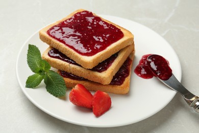 Photo of Toasts served with tasty jam, mint and strawberry on light marble table