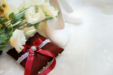 Beautiful wedding bouquet, shoes and decorative pillow with wedding rings on light background