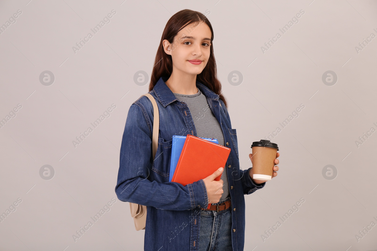 Photo of Teenage student with backpack, books and cup of coffee on grey background