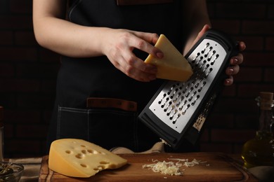 Woman grating cheese at wooden table, closeup