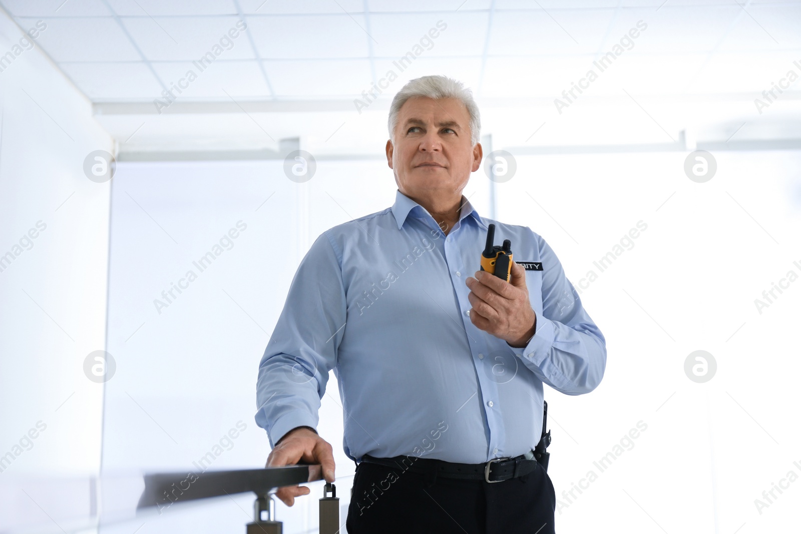 Photo of Professional security guard with portable radio set indoors