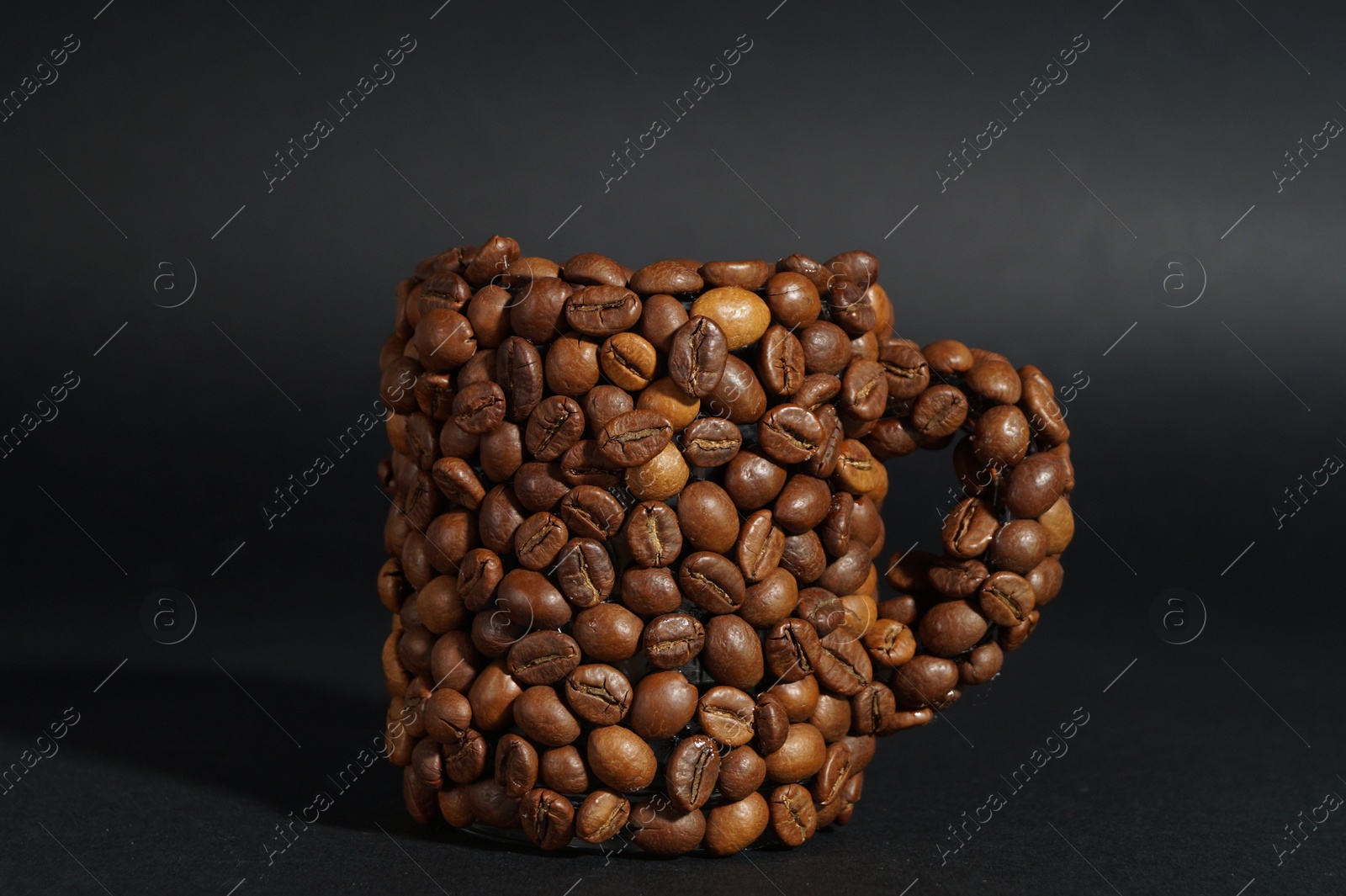 Photo of Cup made of coffee beans against black background