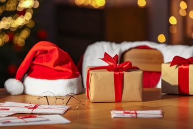 Photo of Santa's Claus workplace. Christmas gifts, letters on table and costume in room