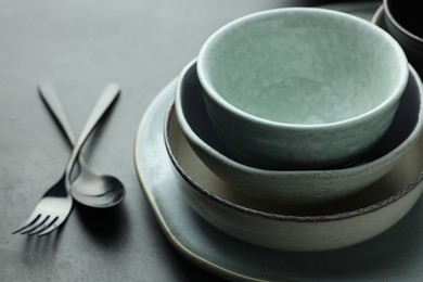 Stylish empty dishware and cutlery on grey table, closeup