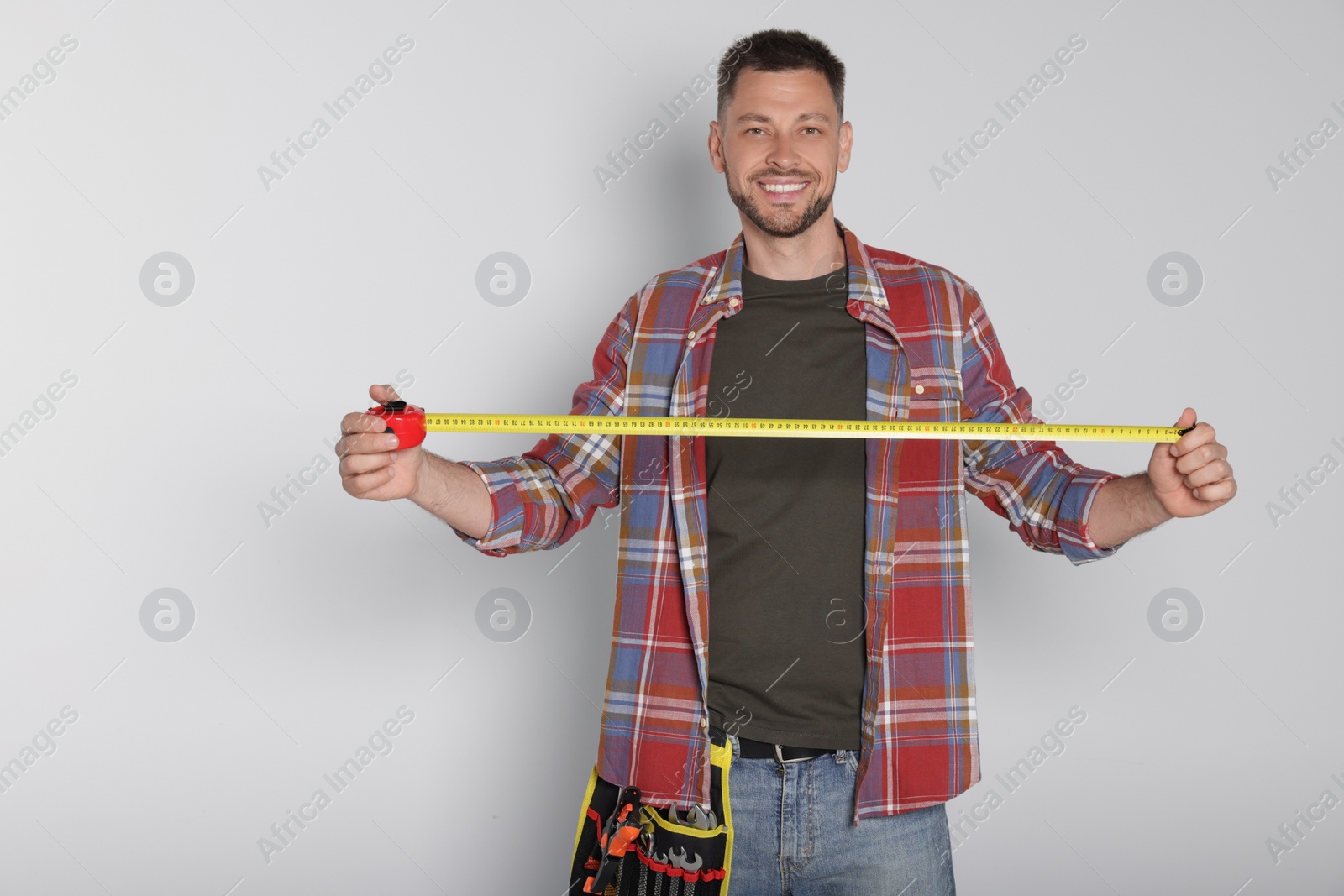 Photo of Handsome worker with measuring tape on white background