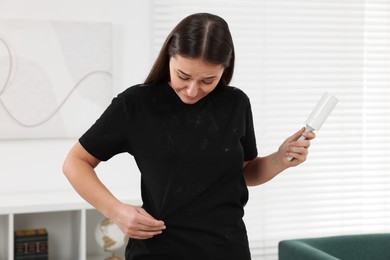 Woman with lint roller and pet hair on her black clothers at home