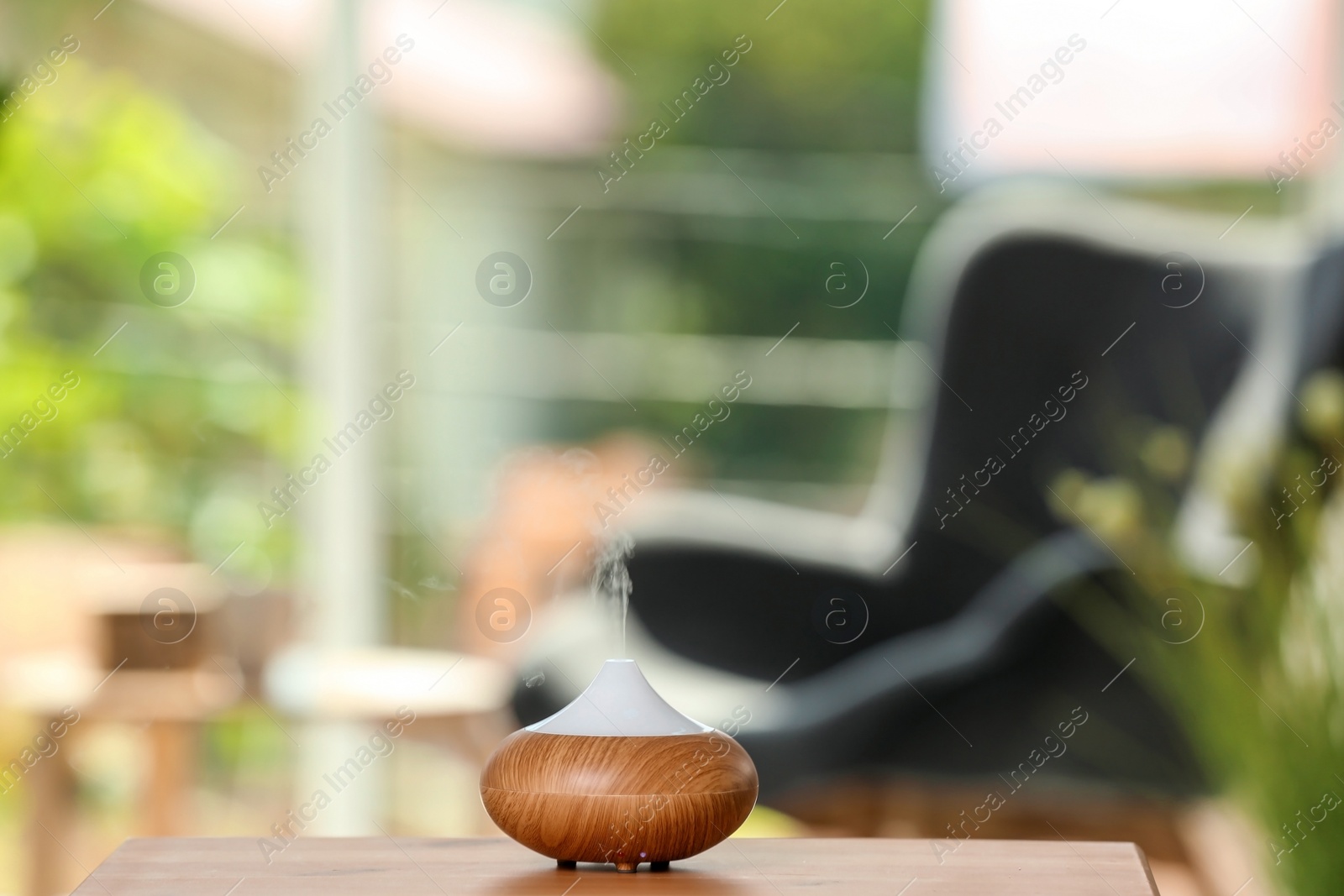 Photo of Aroma oil diffuser lamp on table against blurred background