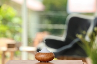 Photo of Aroma oil diffuser lamp on table against blurred background