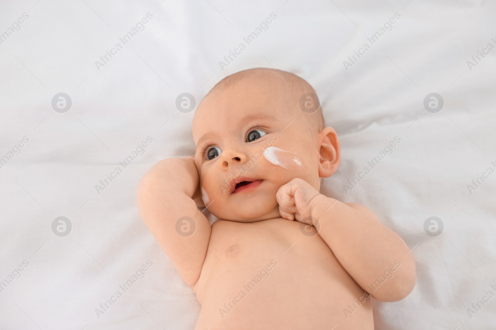 Photo of Cute little baby with cream on face on white blanket