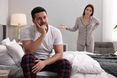 Photo of Offended husband ignoring his wife in bedroom, selective focus. Relationship problems