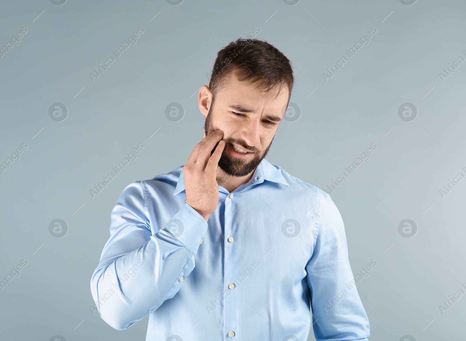 Photo of Young man suffering from toothache on light background