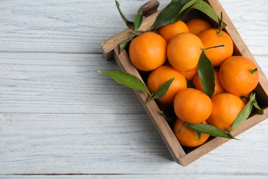 Photo of Crate with fresh ripe tangerines and space for text on wooden background, top view