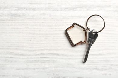 Key with trinket in shape of house on wooden background. Real estate agent services