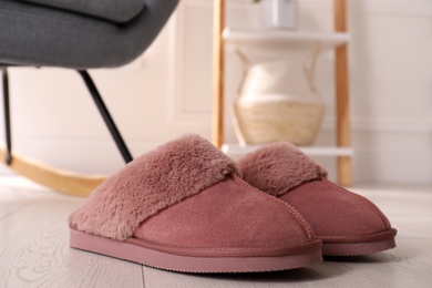 Photo of Pink warm slippers on floor in room