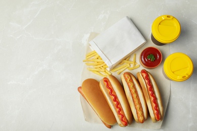 Photo of Tasty hot dogs, french fries and drinks on table, top view. Space for text