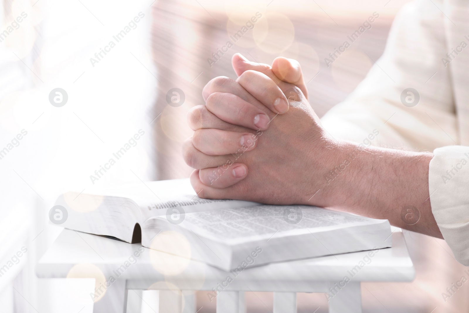 Image of Religion. Christian man praying over Bible at table, closeup