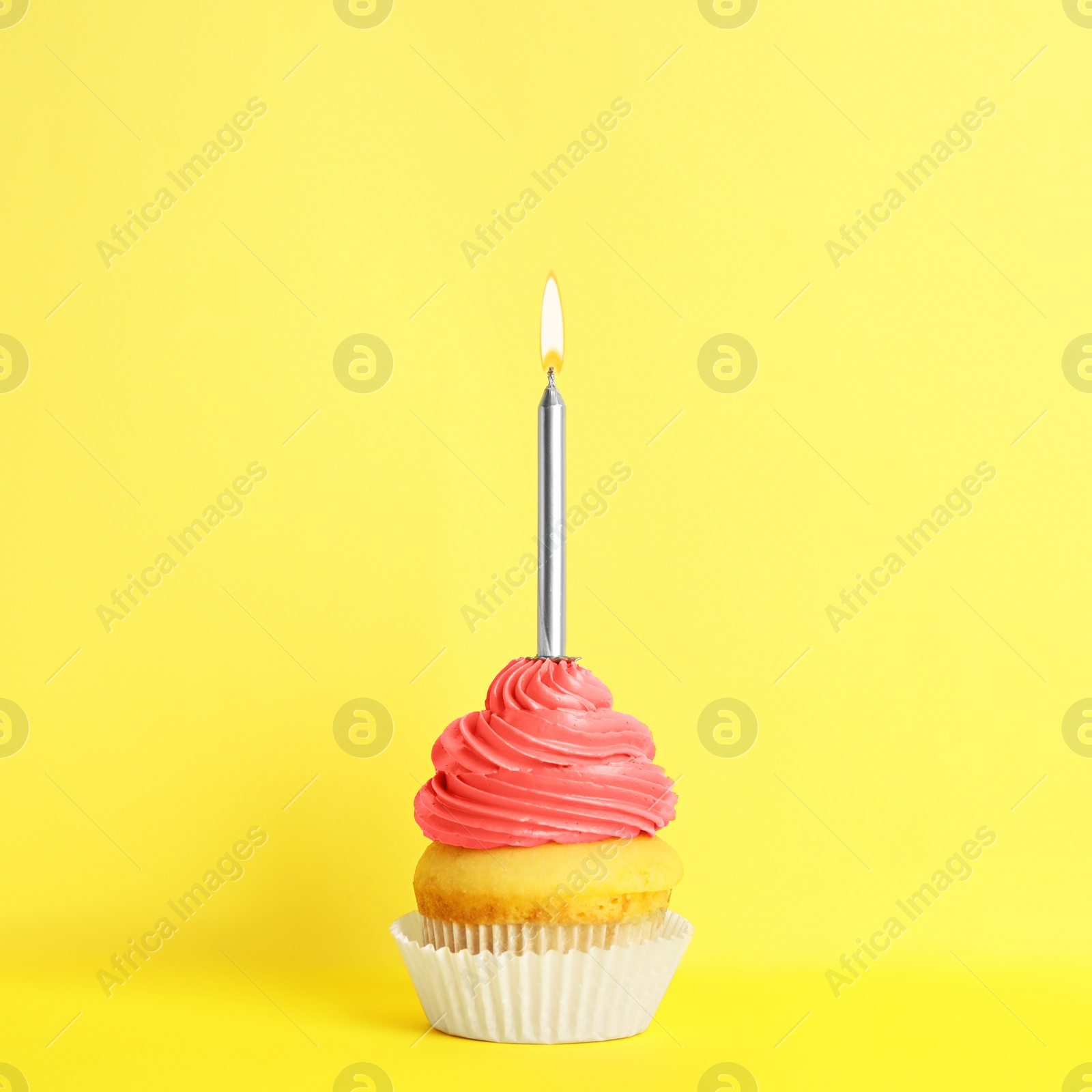 Photo of Birthday cupcake with candle on yellow background