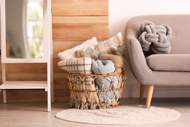 Photo of Basket with blankets and pillows near sofa indoors