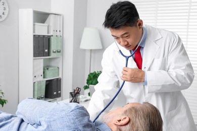 Photo of Doctor examining senior patient with stethoscope in clinic