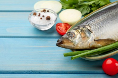 Photo of Delicious salted herring and ingredients on light blue wooden table, closeup. Space for text