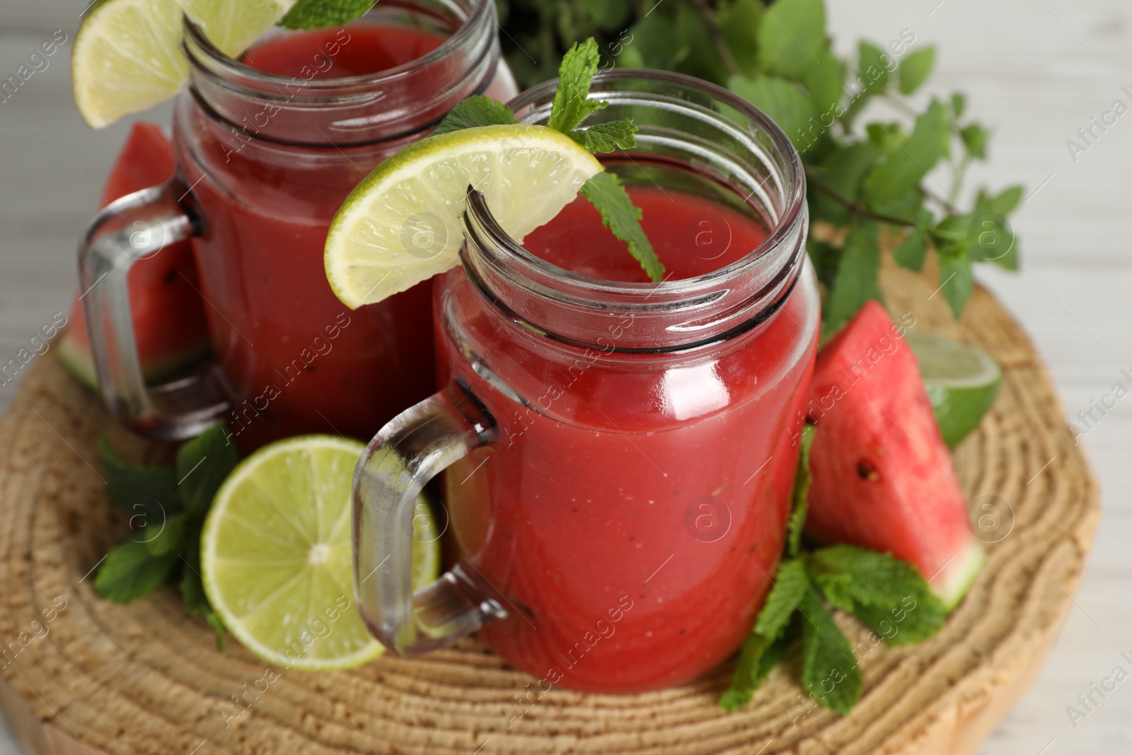 Photo of Tasty summer watermelon drink, limes and mint on white wooden table, closeup