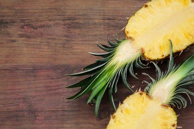 Photo of Halves of delicious ripe pineapple on wooden table, flat lay. Space for text