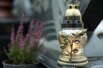 Photo of Grave light and potted heather on granite tombstone at cemetery, closeup