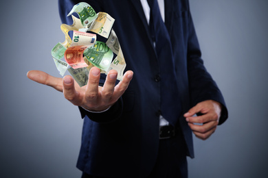 Image of Businessman with money on grey background, closeup. Currency exchange