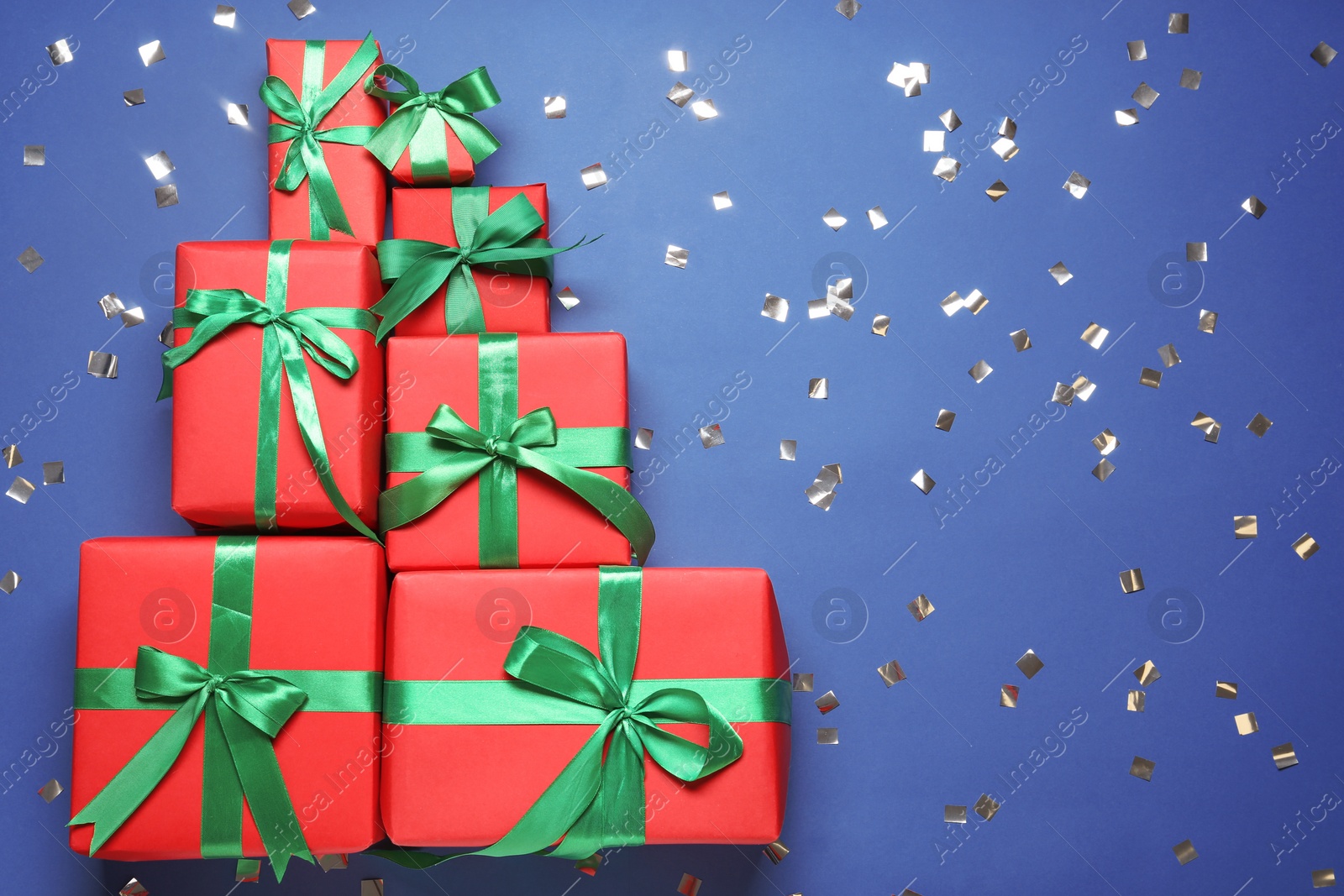 Photo of Christmas tree made with different gift boxes on blue background, flat lay. Space for text