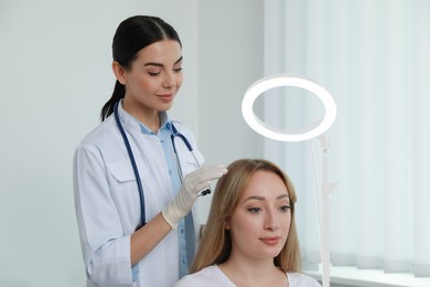 Photo of Young woman visiting trichologist in light clinic