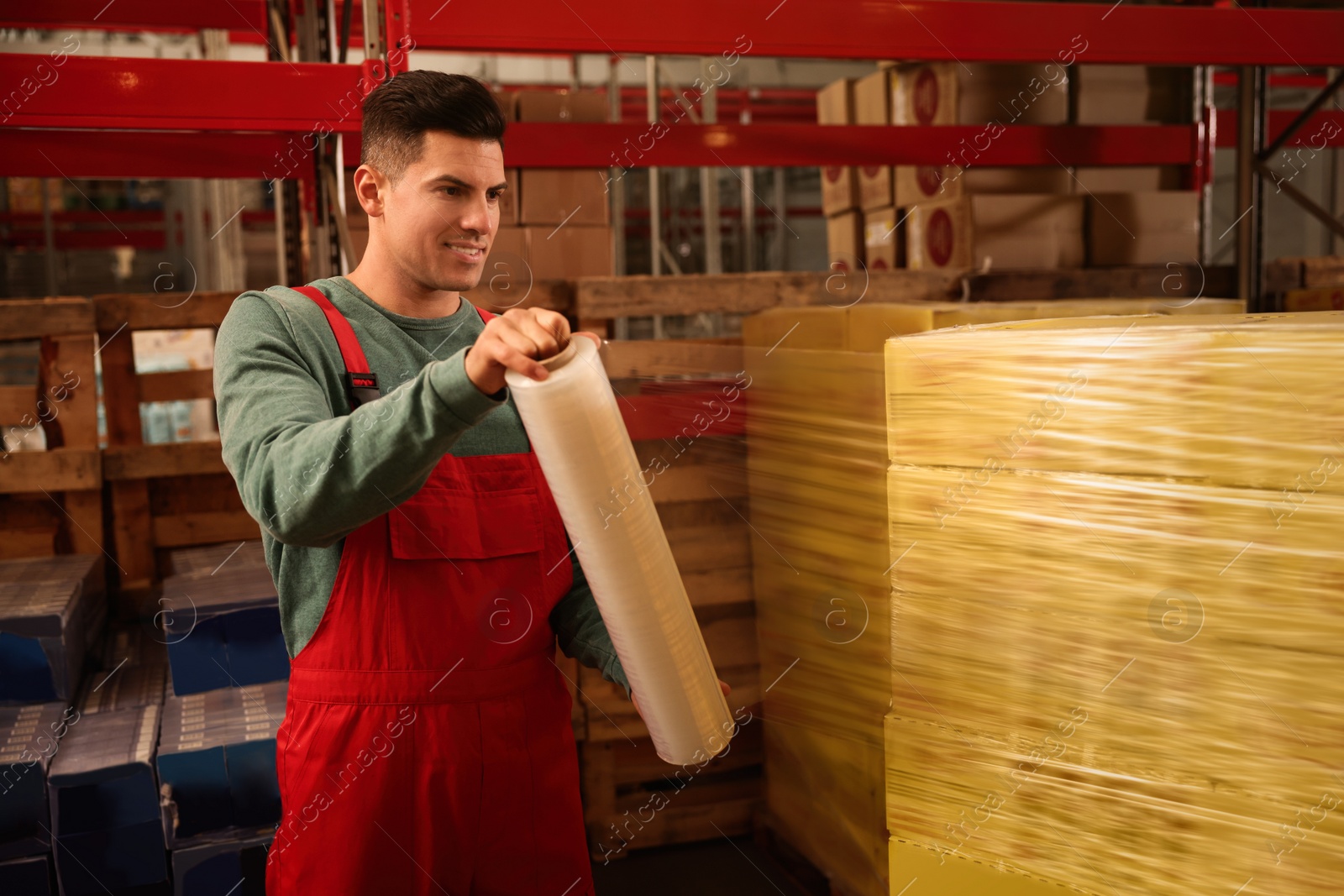 Photo of Worker wrapping boxes in stretch film at warehouse