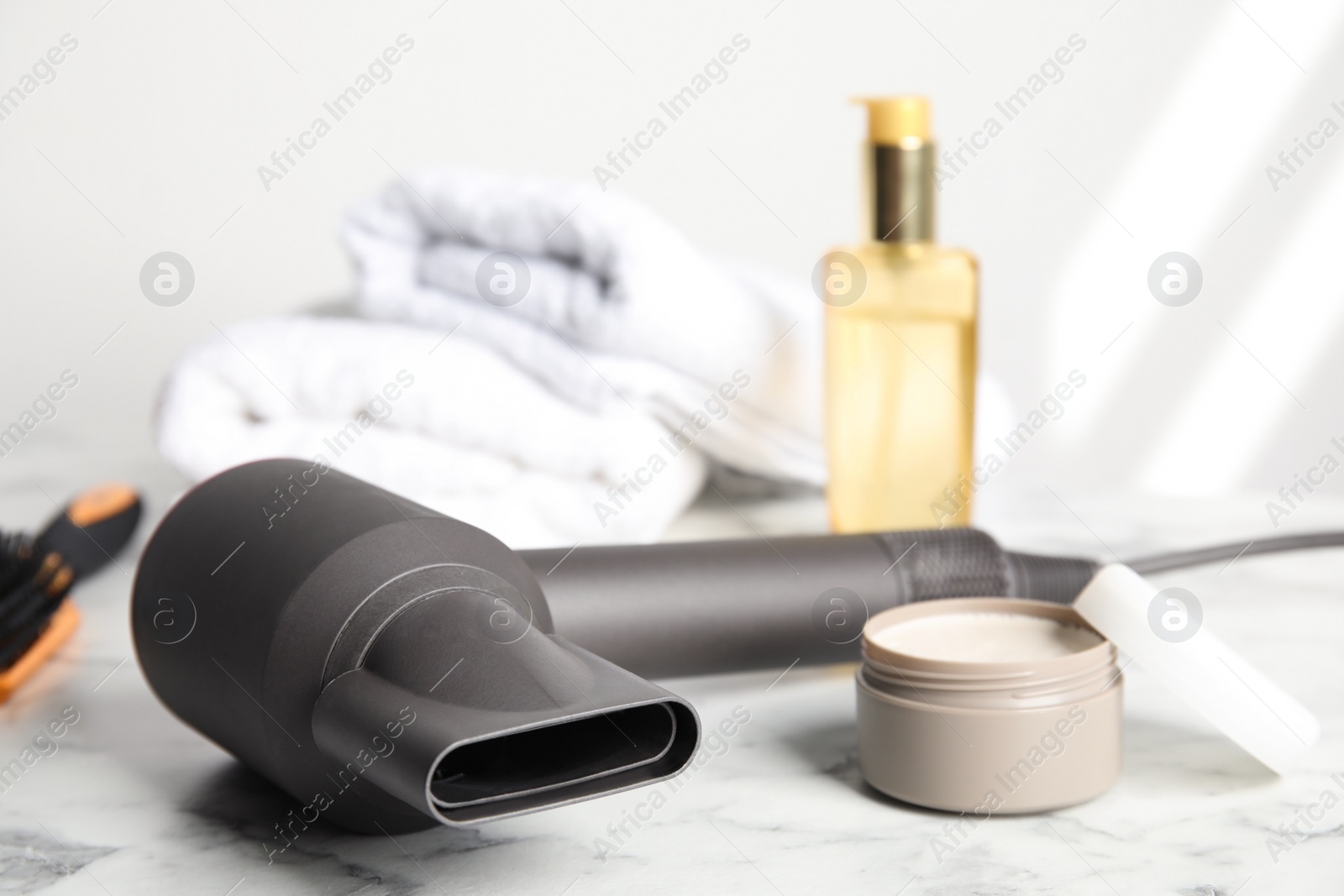 Photo of Hair care products and dryer on white marble table, space for text