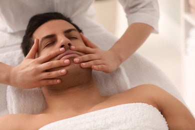 Photo of Man receiving facial massage in beauty salon