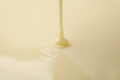 Photo of Closeup view of pouring condensed milk. Dairy product