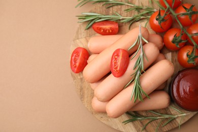 Photo of Delicious boiled sausages, tomato sauce, tomatoes and rosemary on beige table, top view. Space for text