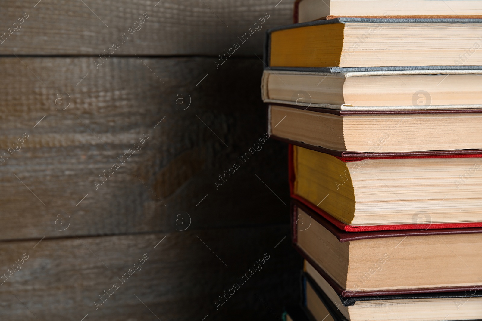 Photo of Stack of hardcover books on wooden background, closeup. Space for text