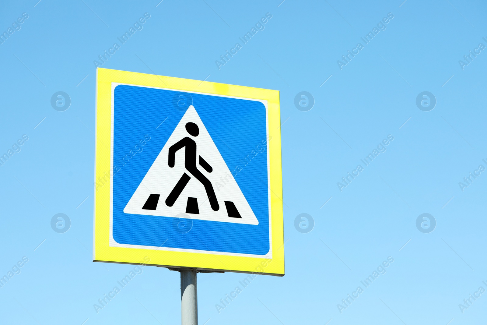 Photo of Post with Pedestrian Crossing traffic sign against blue sky on sunny day. Space for text