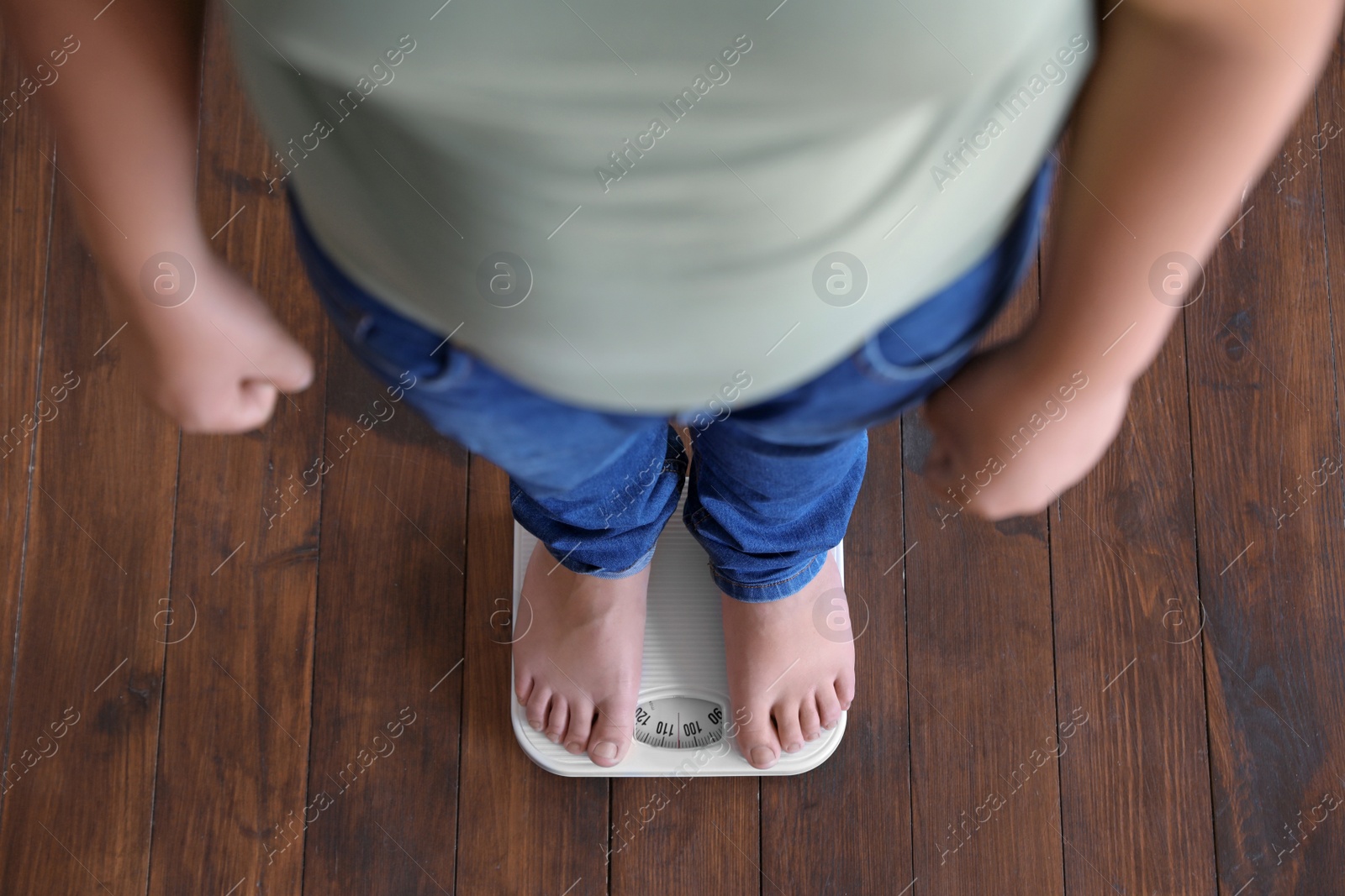 Photo of Overweight boy standing on floor scales indoors, above view