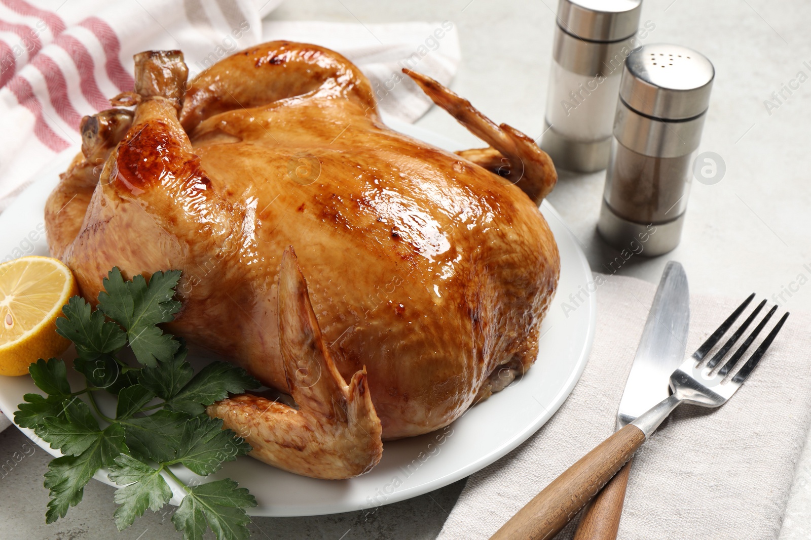 Photo of Tasty roasted chicken with parsley and lemon served on light grey table