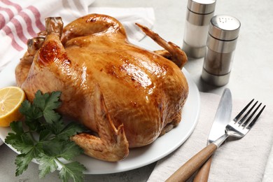 Tasty roasted chicken with parsley and lemon served on light grey table