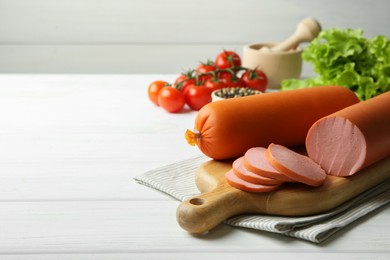 Photo of Board with tasty boiled sausages and products on white wooden table. Space for text