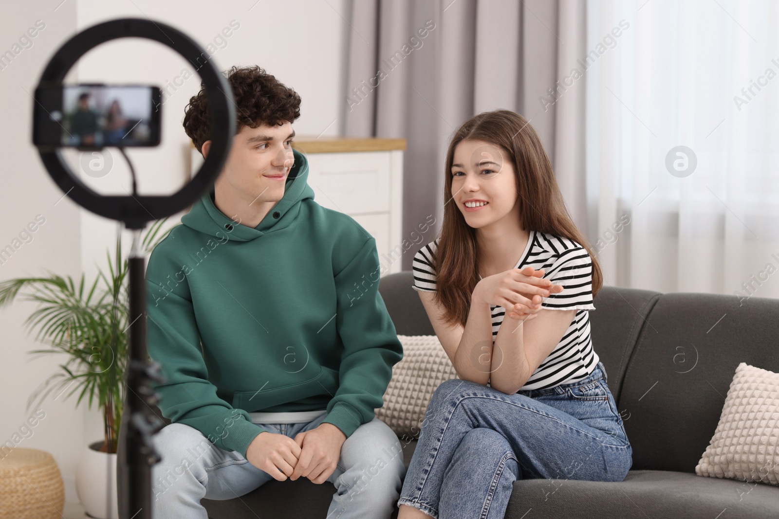 Photo of Smiling teenage bloggers talking while streaming at home