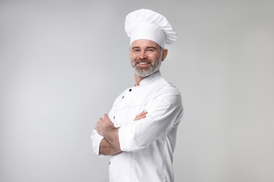 Photo of Happy chef in uniform on grey background