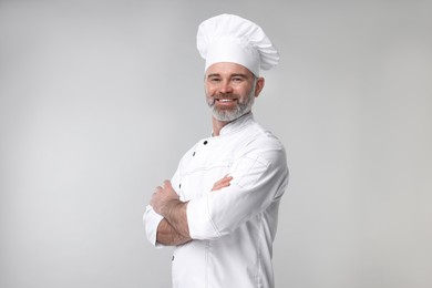 Happy chef in uniform on grey background