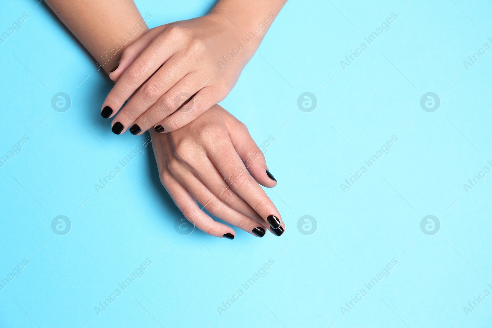 Photo of Woman showing black manicure on color background, space for text. Nail polish trends