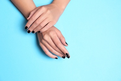 Woman showing black manicure on color background, space for text. Nail polish trends