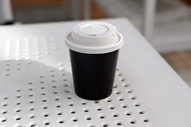 Takeaway paper cup with plastic lid on white table