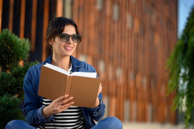 Young woman reading book on city street