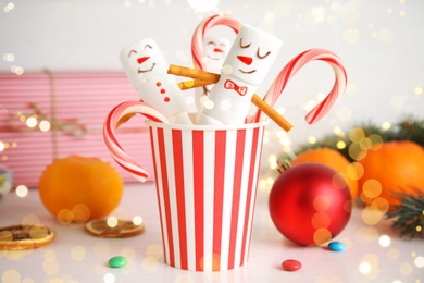 Image of Funny snowmen made of marshmallows in paper cup on white table. Bokeh effect 